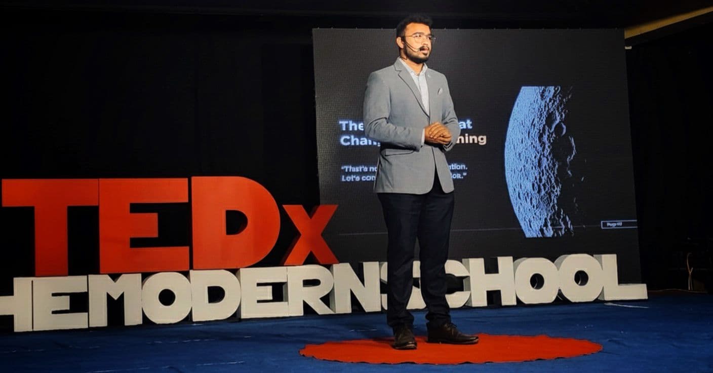 Kshitij on the TEDx stage with a Moon slide behind him